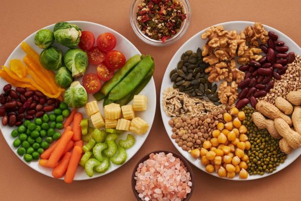 Vibrant display of assorted vegetables, legumes, nuts, and seeds on plates, perfect for healthy eating images.
