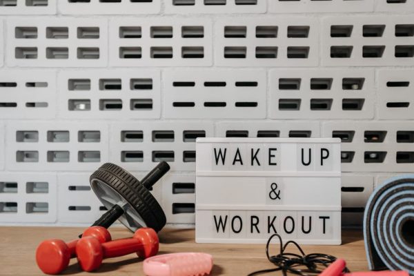 Fitness gear and motivational sign in home gym setup against a brick wall.